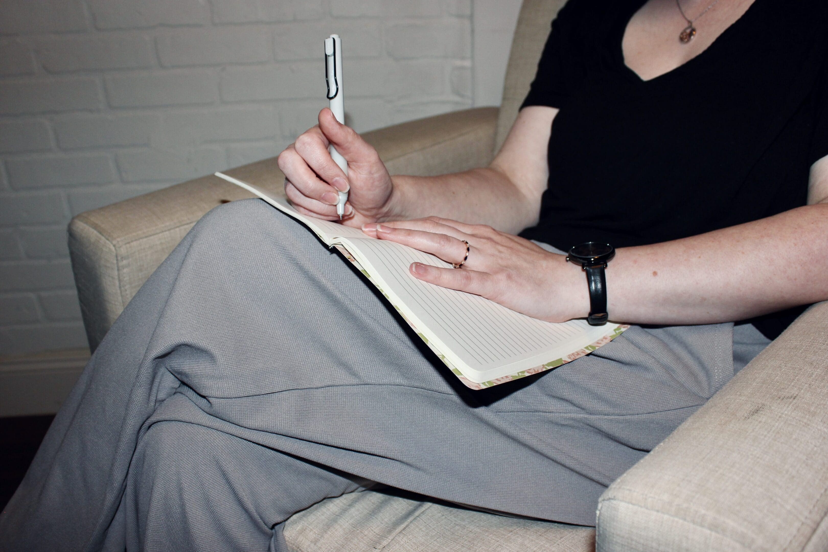 Person writing in a notebook while seated comfortably.